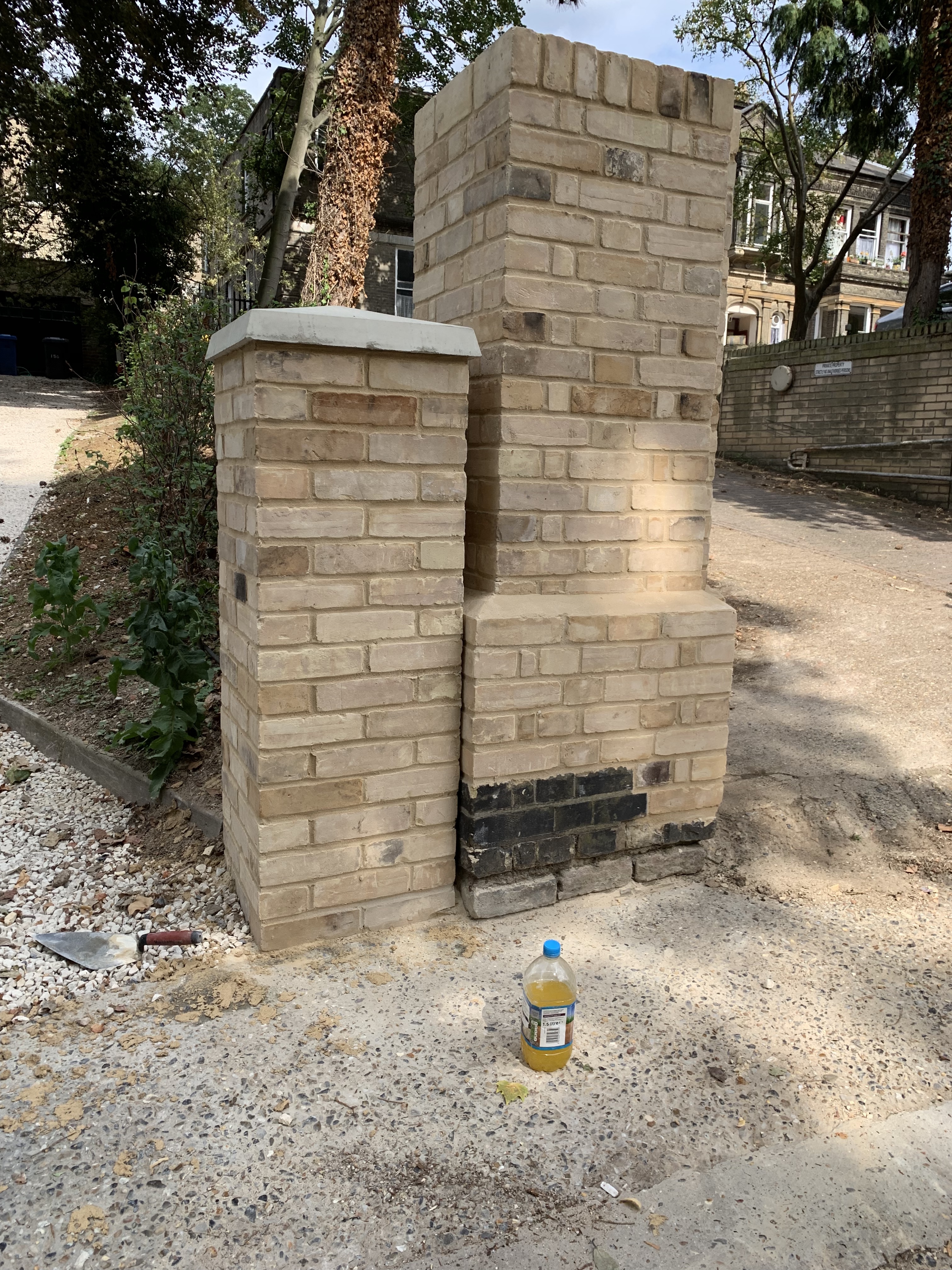 Newly built tan-brick gate pillar with a concrete cap
